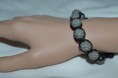 Bracelet fashion gris sur cordon noir.